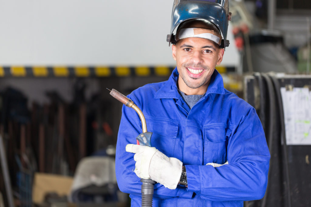 Professional welder posing with wellding machine and torch